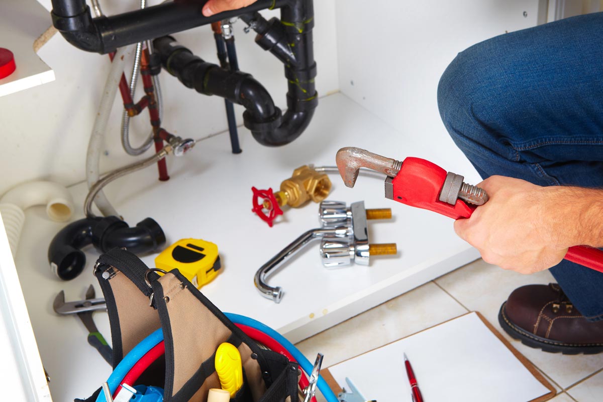 Residential plumbing connections being checked for leaks and maintenance issues