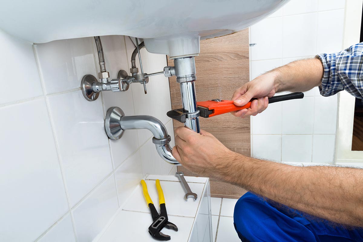 Plumber working on residential plumbing beneath a kitchen sink
